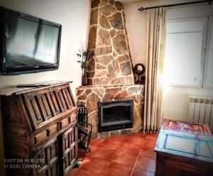 洛索亚Casa Sierra Norte Madrid的客厅设有石制壁炉和平面电视。