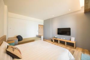 小琉球岛小火鸡旅店的一间卧室配有一张床和一台平面电视
