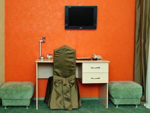 巴尔瑙尔亚历山大之家酒店的客房设有一张桌子、一台电视和一把椅子