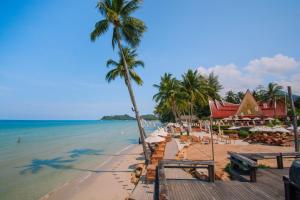 象岛Santhiya Tree Koh Chang Resort的海滩上,有椅子和棕榈树,还有大海