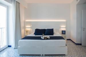 维耶特里劳埃德拜亚酒店的卧室配有带蓝色枕头的大型白色床