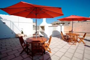 斯佩基亚Appartamenti Fusaro的庭院里配有两张桌子和椅子以及红伞