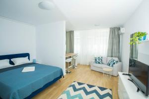 布加勒斯特Residence DP Pipera的一间卧室配有一张床、一台电视和一张沙发
