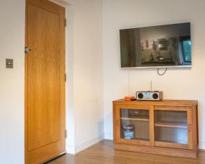 阿克菲尔德2 Ringles Place的客房设有木柜,墙上配有电视。