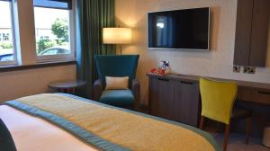 普雷斯蒂克卡尔登酒店的酒店客房配有一张床、一张书桌和一台电视。