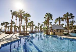 沙姆沙伊赫Elegant Apartment in a Luxury Resort的一座棕榈树游泳池和一座建筑