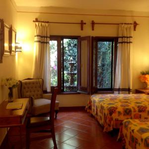 瓦哈卡市Hotel Maela的一间卧室配有一张床、一把椅子和窗户。