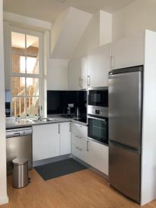 布拉加Carmo House的厨房配有白色橱柜和不锈钢冰箱