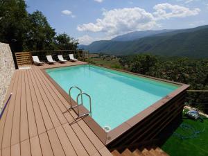 Fagnano AltoCastello di Fagnano -Albergo Diffuso & SPA的一座位于木质甲板上的游泳池,甲板上以群山为背景