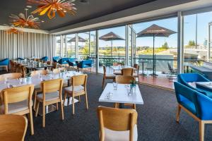 卡瓦纳华特斯Mercure Sunshine Coast Kawana Waters的餐厅设有桌椅和窗户。