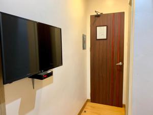 达沃市Davao Persimmon Suites的挂在门旁墙上的平面电视