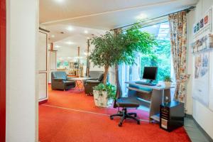 霍夫霍夫品质酒店的一间办公室,办公室里配有书桌和一台电脑,铺在红地毯上