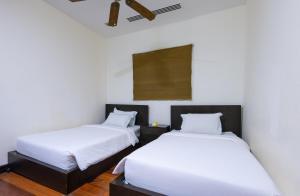 哥打京那巴鲁沙巴海滩别墅套房 的配有白色墙壁和木地板的客房内的两张床