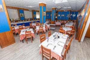 廖洛泰尔梅克里斯塔洛酒店的一间设有白色桌椅的用餐室和蓝色的墙壁