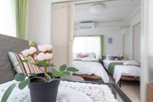 东京Uhome Iriya Apartment的一间设有一张桌子的房间,配有一个粉红色玫瑰花瓶