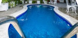Santa Rosa de LimaHotel Mediterraneo Inn的一个带蓝色水和白色椅子的游泳池