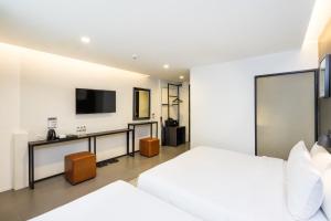 曼谷马尔温空间旅馆的一间卧室配有一张床,墙上配有电视