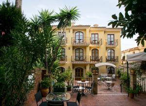 克雷克塞利马斯耶塔餐厅酒店的一座黄色的建筑,配有桌椅和树木