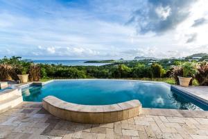 维约堡Emerald Vista Villa的一个带长凳的游泳池,背景是大海