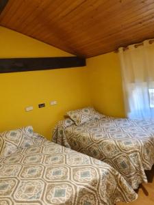 OricáinHostal Rural Oricáin的配有两张床的客房,设有黄色的墙壁和窗户