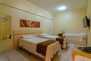 贝洛奥里藏特Villa Neves Residence的一间医院间 - 带两张床和电视