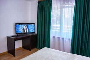阿尔杰什河畔库尔泰亚Hotel THR Center的一间卧室配有电视和绿色窗帘
