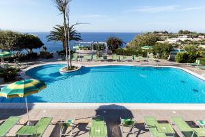 梵蒂冈角Hotel Residence Sciaron的一个带椅子和遮阳伞的游泳池以及大海