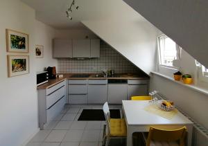 特里尔Ferienwohnung Grete的厨房配有白色橱柜和一张带黄色椅子的桌子