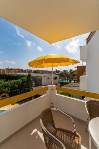 卡拉米洛Apartamentos Mallorca SL的阳台的黄色遮阳伞,配有桌椅
