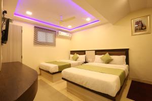 孟买快乐岛酒店的一间卧室设有两张床和一个紫色的天花板