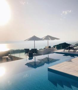 KechriaVilla Salina Luxury Pool Villa的游泳池配有椅子和遮阳伞,水中
