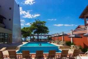 瓜拉图巴Spazio Marine Hotel - Guaratuba的游泳池,带椅子,有人游泳