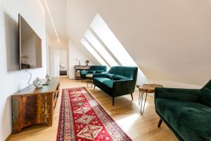 格拉茨Große Dachgeschosswohnung im Herzen von Graz的客厅配有两张绿色沙发和地毯。