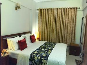 卡拉奇"Service Apartments Karachi" Beach View的一间卧室配有一张带红色枕头的大床
