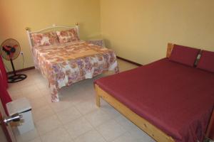 埃斯帕戈斯Rooming house的一间卧室配有两张床和红色的床罩
