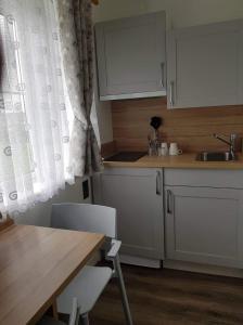 都柏林Cozy Room,Private Bathroom,Private Kitchynete的厨房配有白色橱柜、桌子和水槽。
