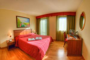 佩斯卡塞罗利Hotel Garnì Posta的一间卧室配有红色的床、一张书桌和一台电视。