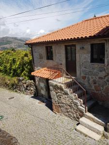 AlamelaCasinha do João no Gerês的石头房子,有红色的屋顶和楼梯