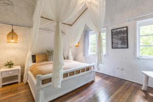 坎古Eco Bamboo Bungalow 4的一间卧室配有一张带天蓬的白色床