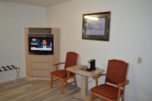 洛杉矶快乐罗杰酒店的客厅配有桌椅和电视。