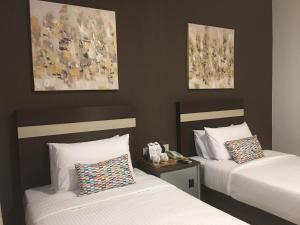 米里车马拉精品酒店的两张床铺,位于酒店客房,墙上挂有绘画作品
