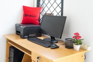 雅加达RedDoorz near Tarumanagara University的一张带电脑显示器和打印机的桌子