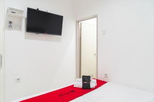 雅加达RedDoorz near Tarumanagara University的白色客房,墙上配有平面电视