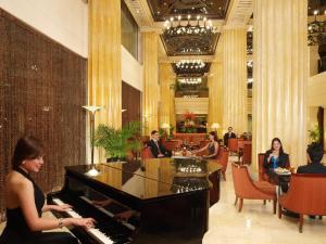 马尼拉The Heritage Hotel Manila的一名在酒店大堂弹钢琴的女人