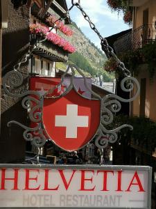 采尔马特Petit Helvetia Budget Hotel的上面有瑞士国旗的酒店标志