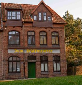 吕讷堡Sülfmeister Haus的红砖房子,设有绿色的门和窗户