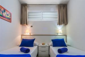 英格兰海滩Alsol Patricio的配有蓝色枕头的客房内的两张床