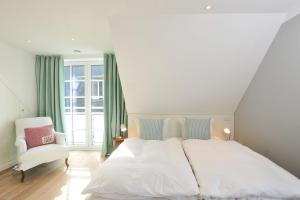 韦斯特兰Luk Hüs的卧室配有白色的床和白色椅子