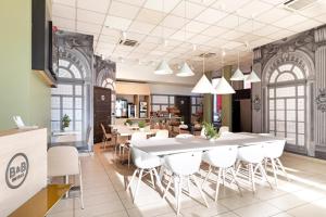 都灵B&B HOTEL Torino Orbassano的一间设有大桌子和白色椅子的用餐室