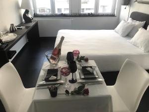 布鲁塞尔Les lofts de Styliste的一间卧室配有一张床和一张桌子及一瓶葡萄酒